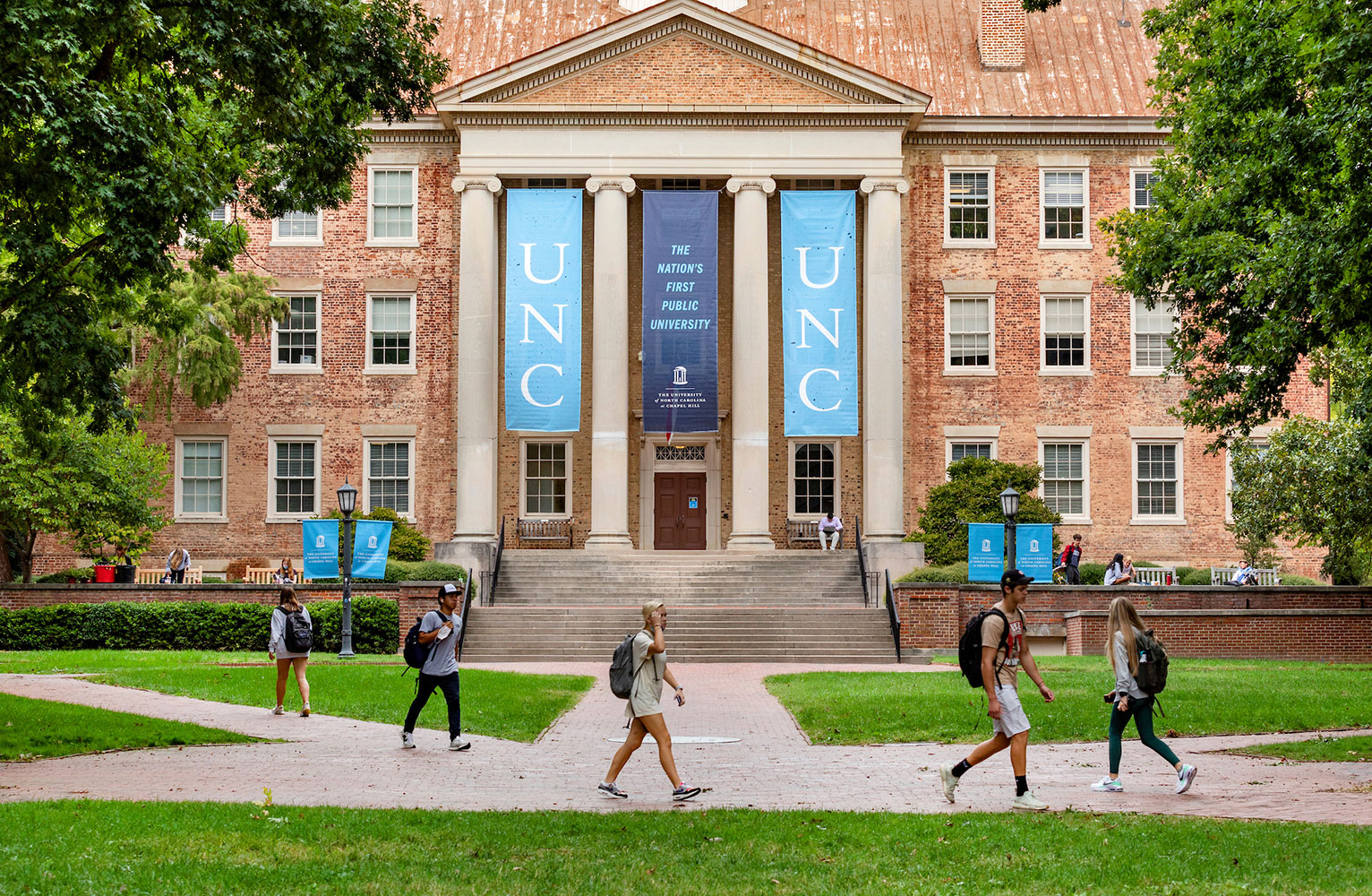 Carolina students traverse campus in the foreground with South Building in the background