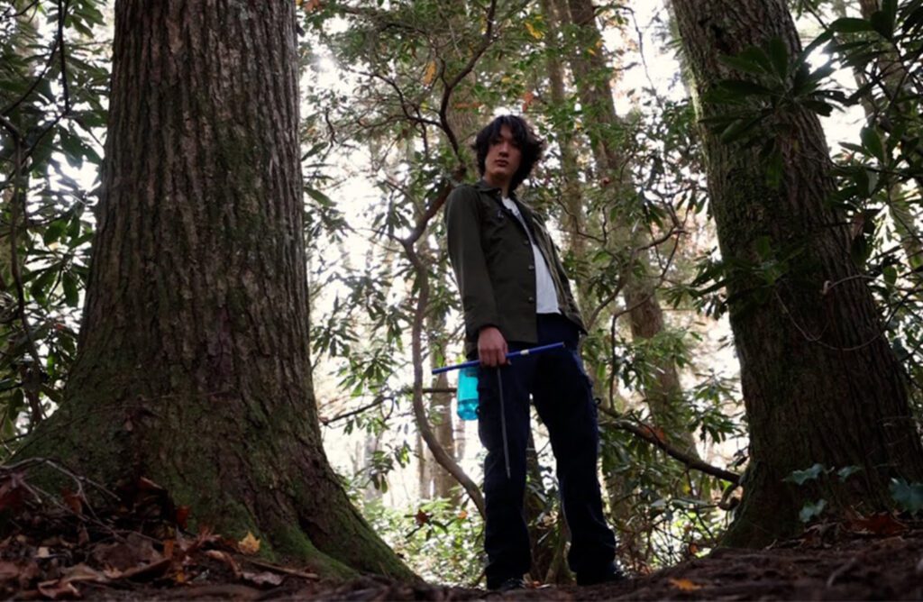Ken Donny-Clark stands in a forest