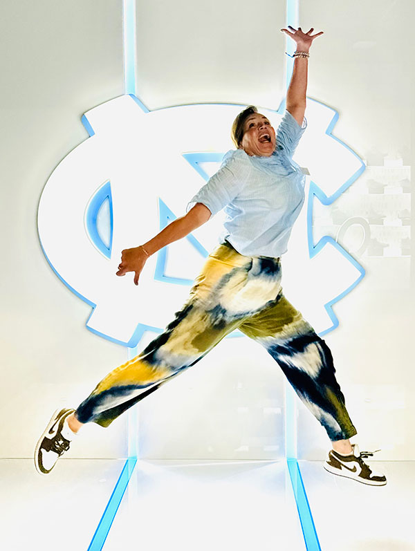 Jane Ellison leaps in the air a la Jumpman with the UNC athletics logo in the background