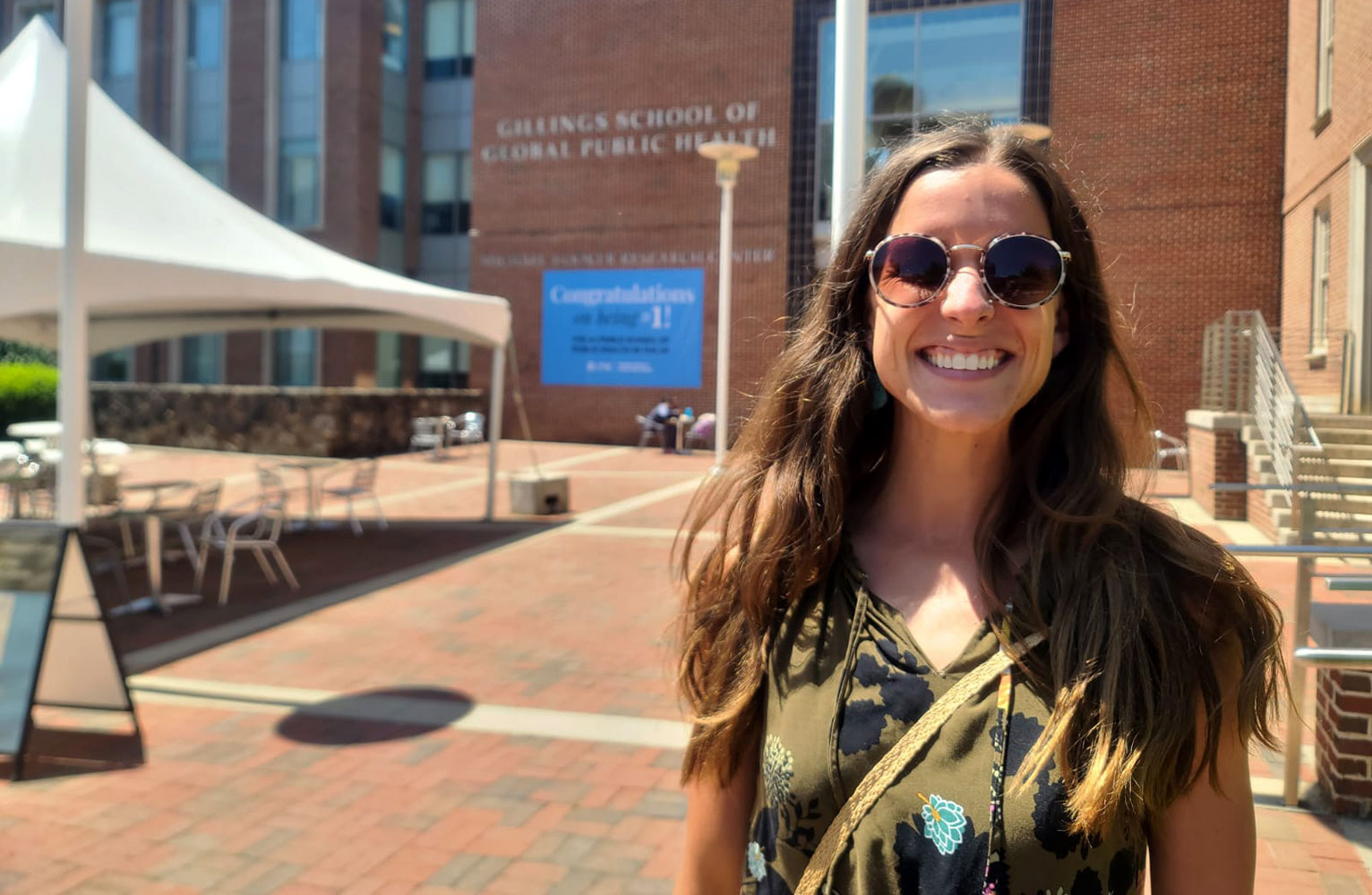 Hanna Brosky smiles at the camera with the Gillings School of Global Public Health courtyard and building in the background