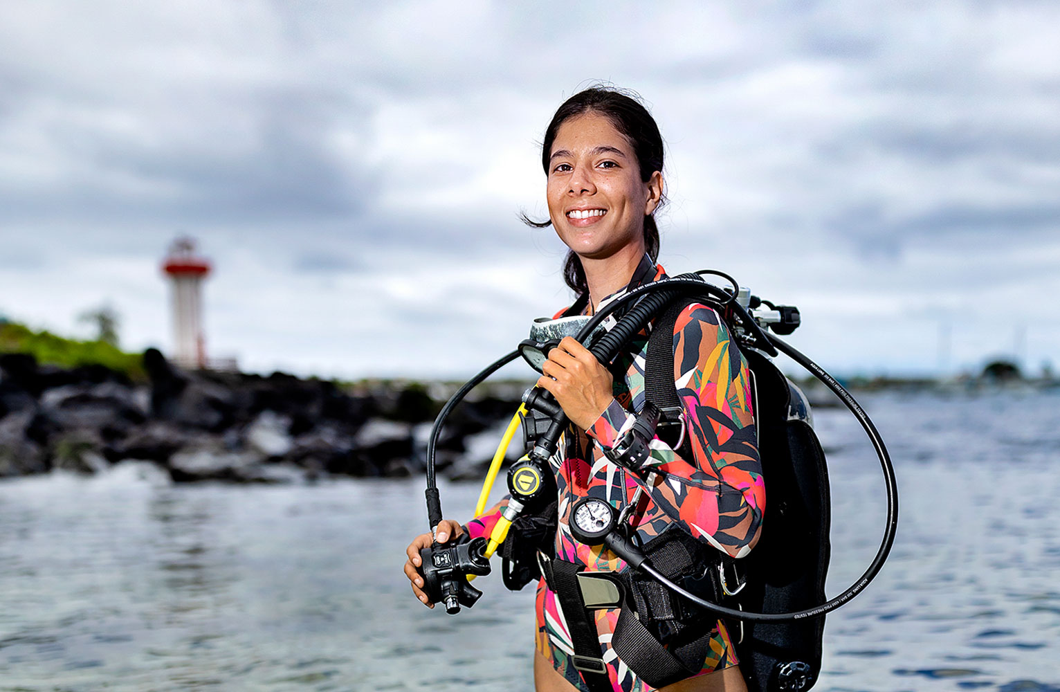 Isabel Silva stands in the ocean facing the camera wearing scuba gear