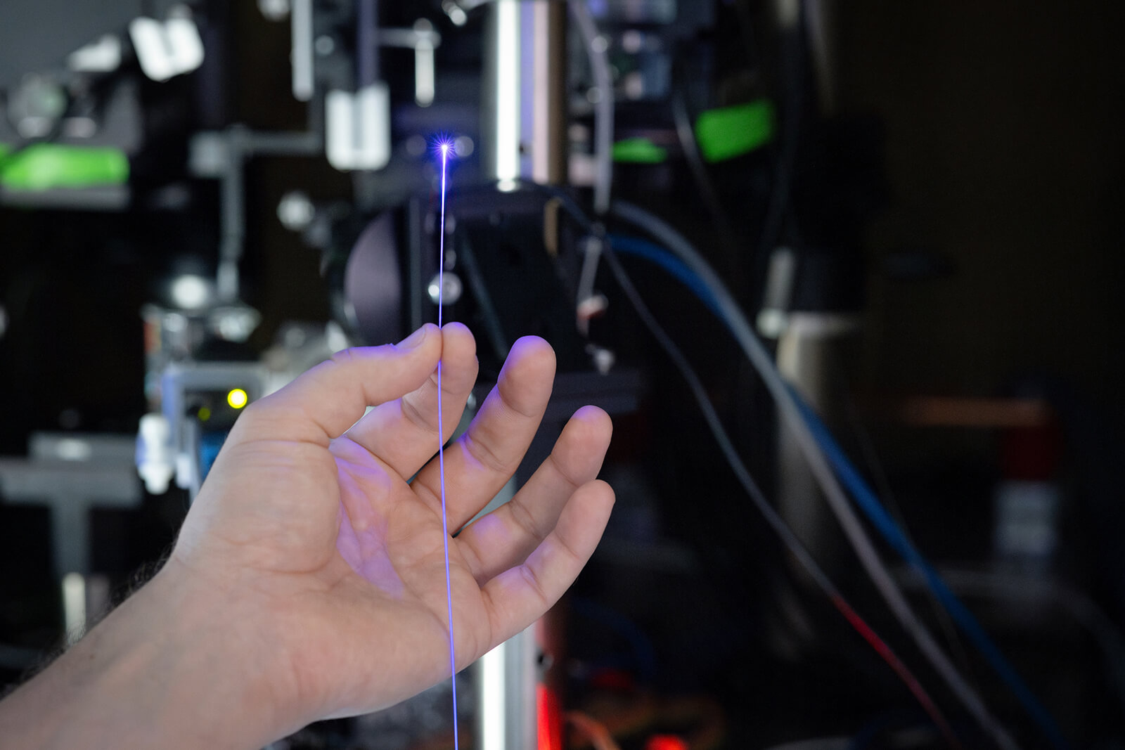 A hand holding a fiber optic cable in a lab