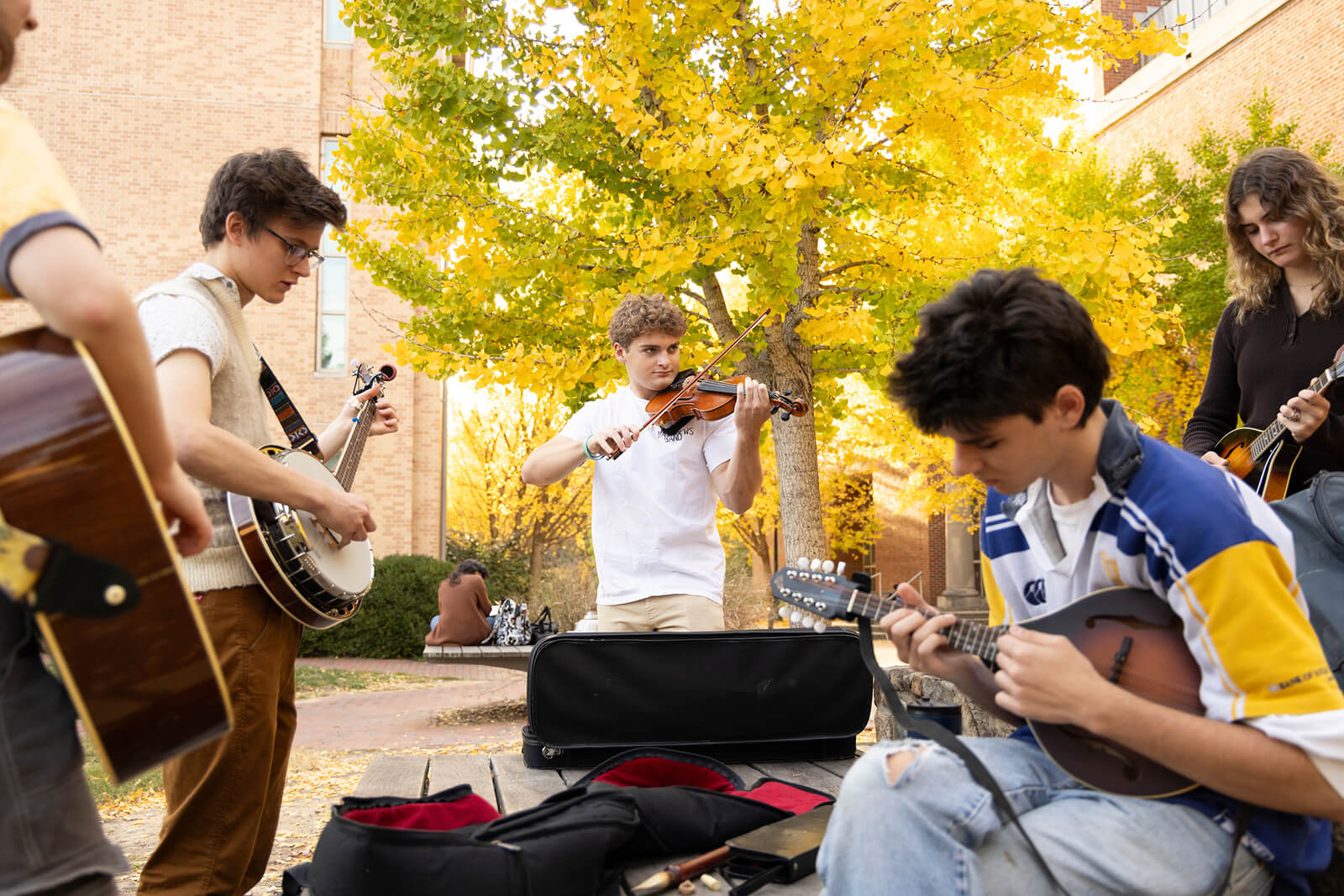 Carolina students playing fiddles and banjos in a circle on campus
