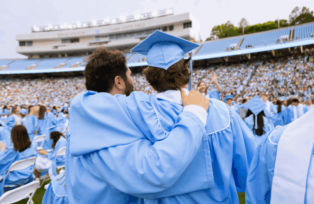 The back of two Carolina graduates with their arms around each other.