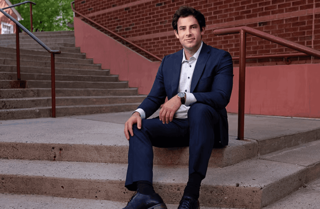 Benny Klein ’25 sitting on stairs wearing a suit