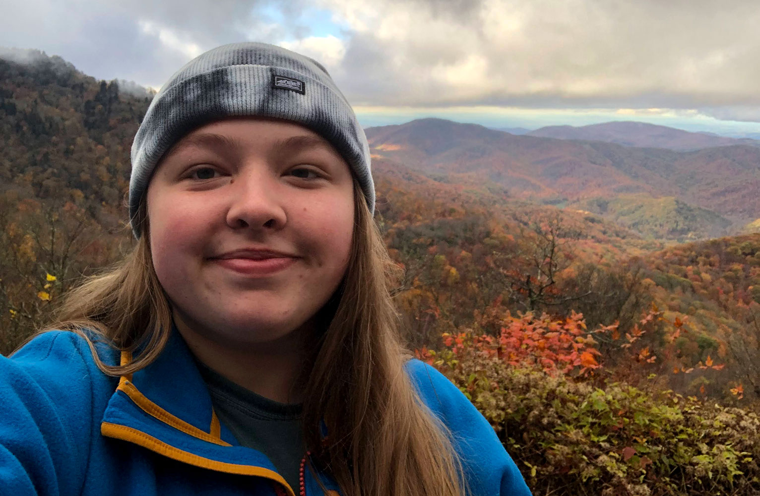 A selfie of Chloe with the western North Carolina mountains in fall in the background