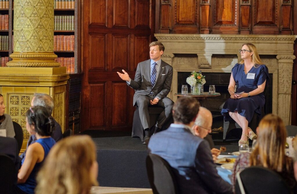 Chancellor and volunteer alumna speak on stage at a formal event.