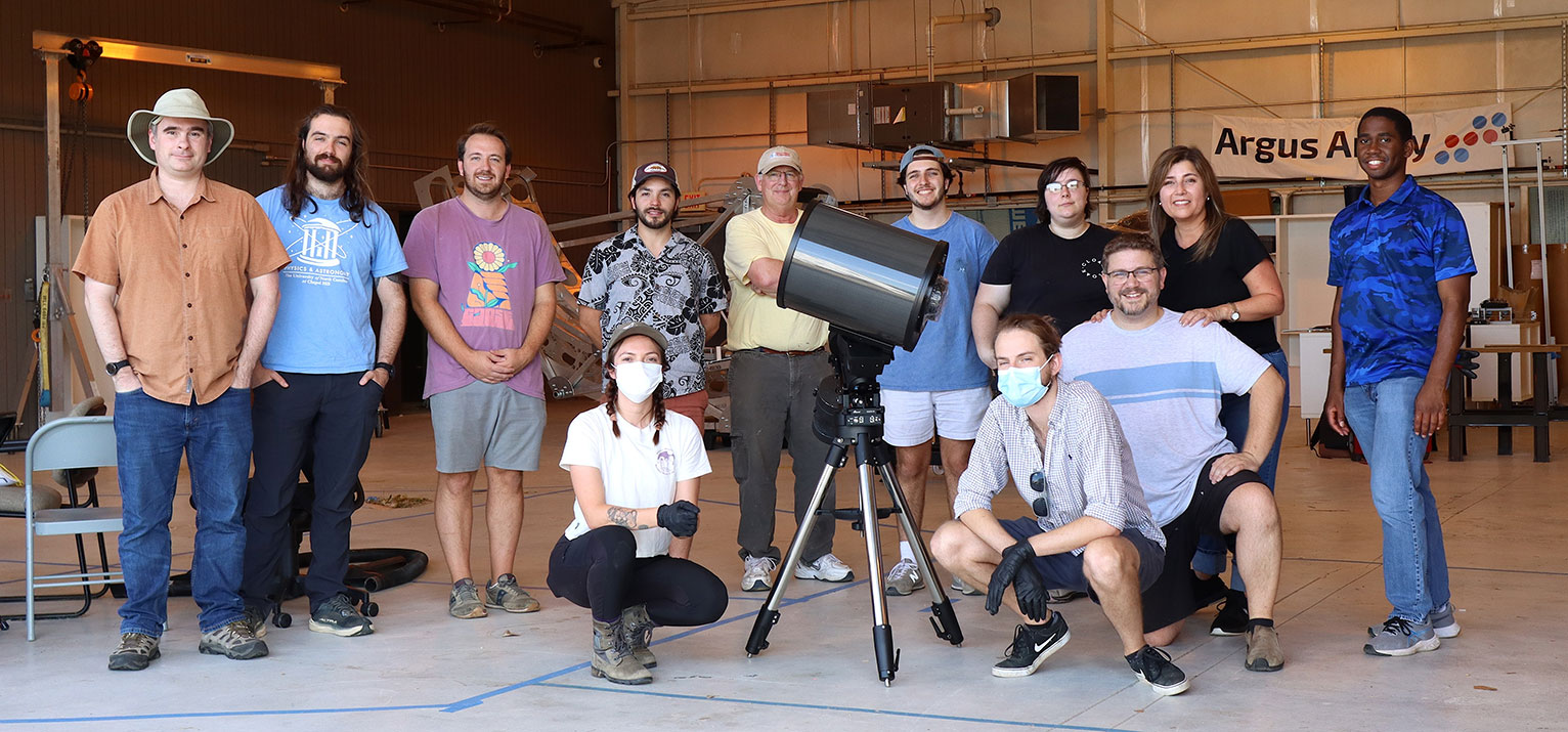 Several Argus Array team members pose with a telescope