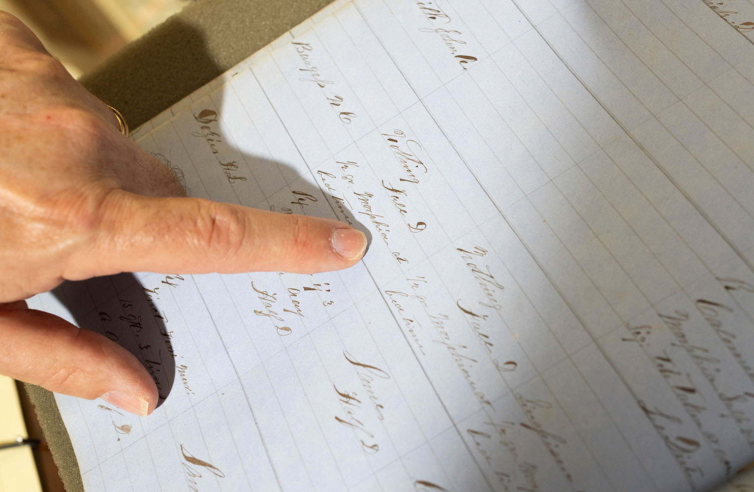 A finger skims the page of a 19th-century doctors' notes in a daybook from the Wilson Special Collections Library