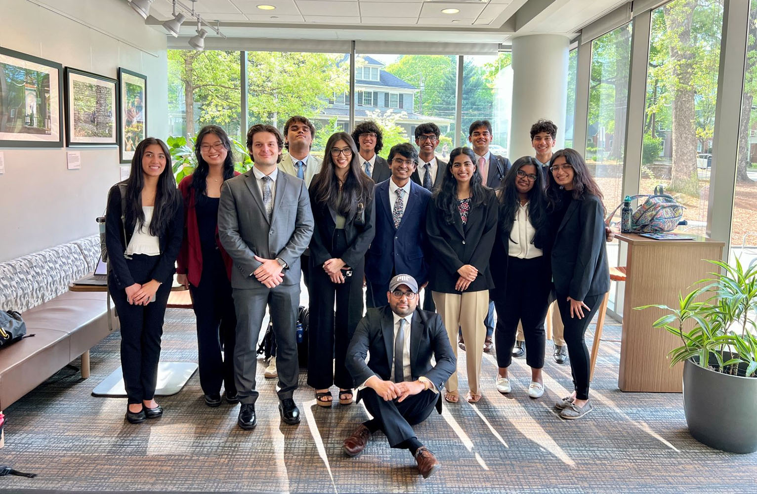 13 Diplomacy Lab students in business attire and pose for a group photo with Professor Neil Gaikwad