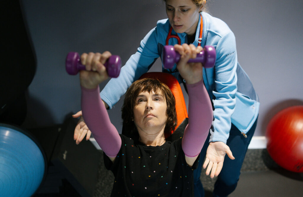 Eli Levene lifting weights with the help of Gabby Brennan.